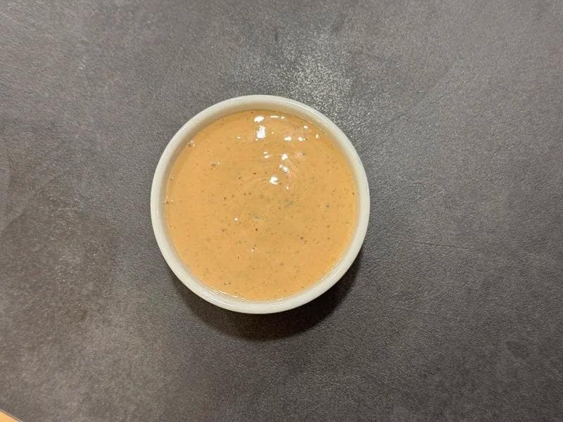 Homemade burger sauce in a white bowl with a creamy tan color and visible spice specks.