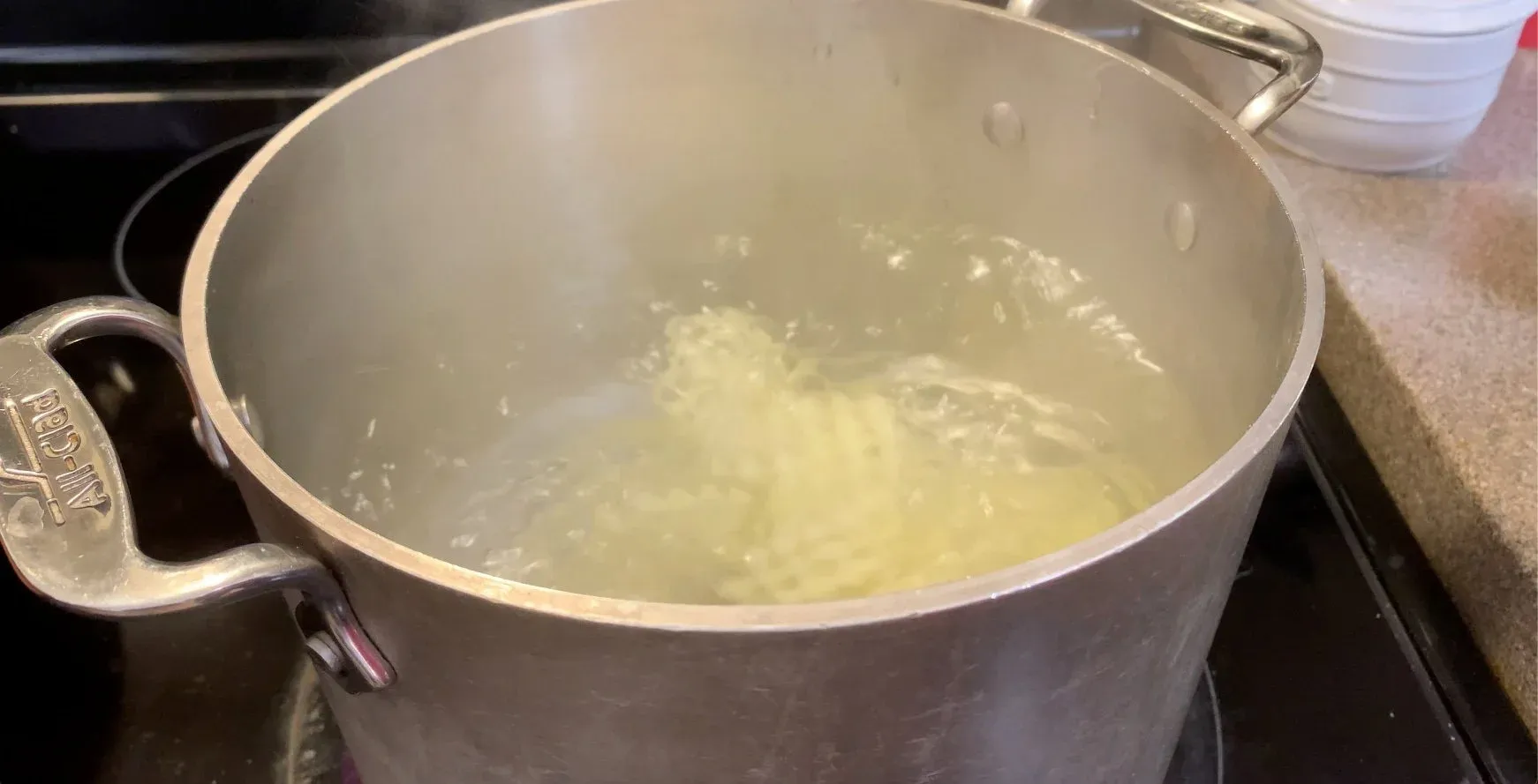 Partially cooked potatoes boiling in a large pot of water on the stovetop.