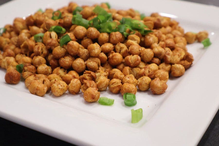 Crispy air fryer roasted chickpeas on a white plate garnished with green onions.