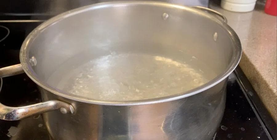 Pot of simmering water on stovetop for blanching spinach.