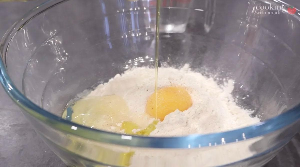 Flour, egg, and olive oil combined in a glass bowl for martabak dough preparation.