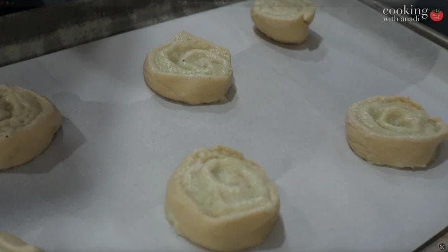 Mashed potato pinwheels sliced from crescent rolls arranged on parchment paper, ready for baking.