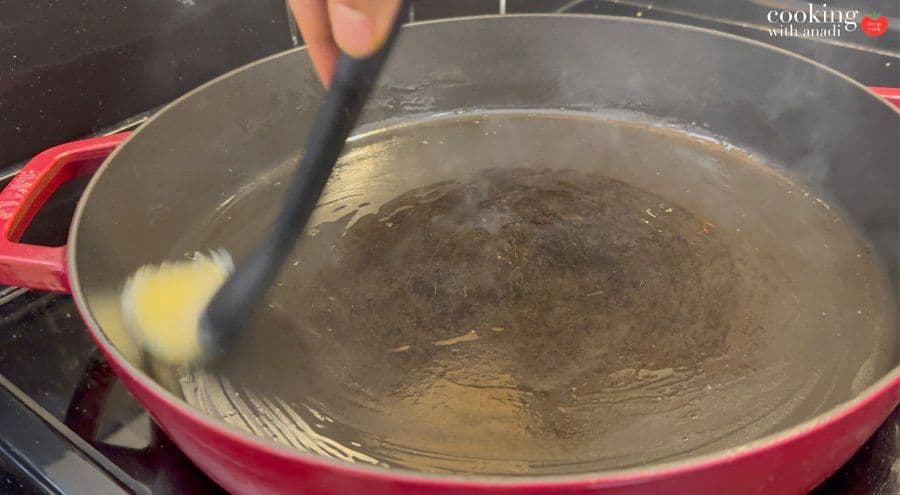 Hot oil sizzling in a red cast-iron pan on medium-high heat, ready for cooking marinated chicken.