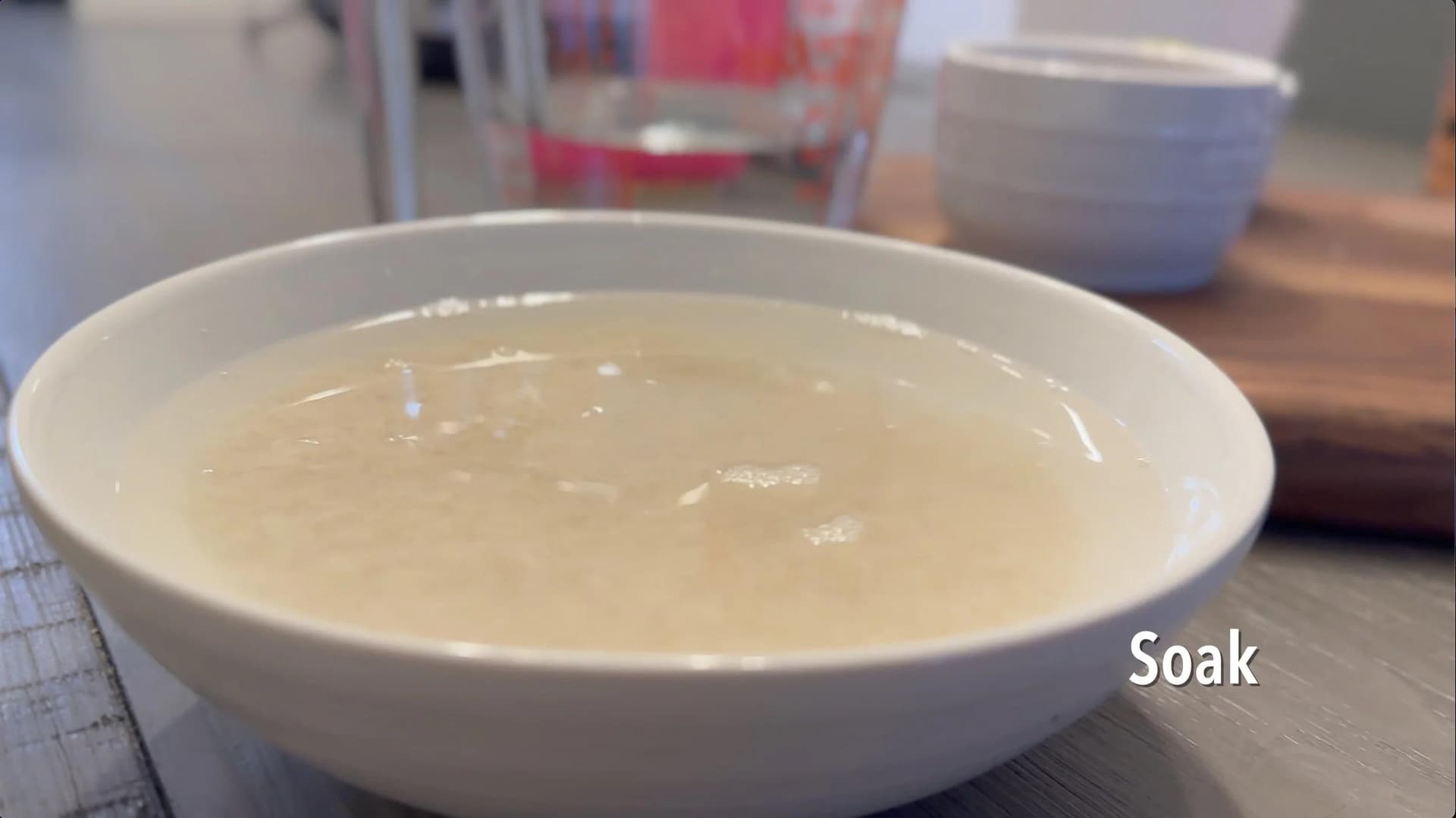 White bowl filled with water and uncooked rice soaking, labeled "Soak"