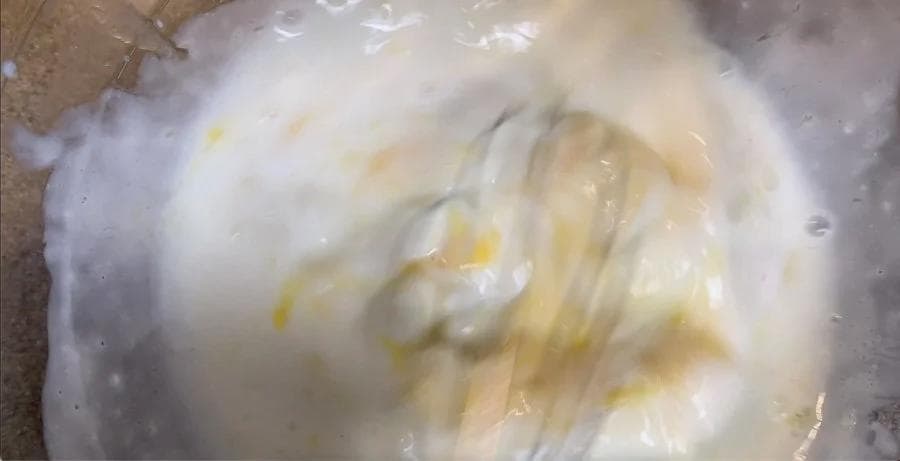 Wet pancake batter ingredients mixed together in a bowl, showing a pale yellow and white mixture with visible butter streaks.