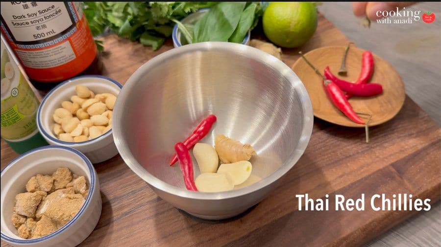 Ingredients for Thai chicken marinade in a metal bowl: garlic, ginger, and red chillies ready to be ground.