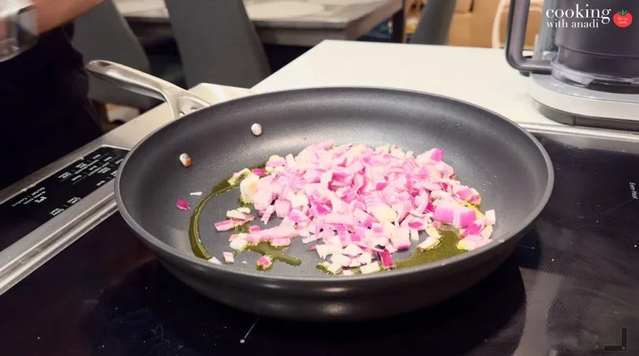 Diced red onion and minced garlic sautéing in avocado oil in a dark nonstick skillet.
