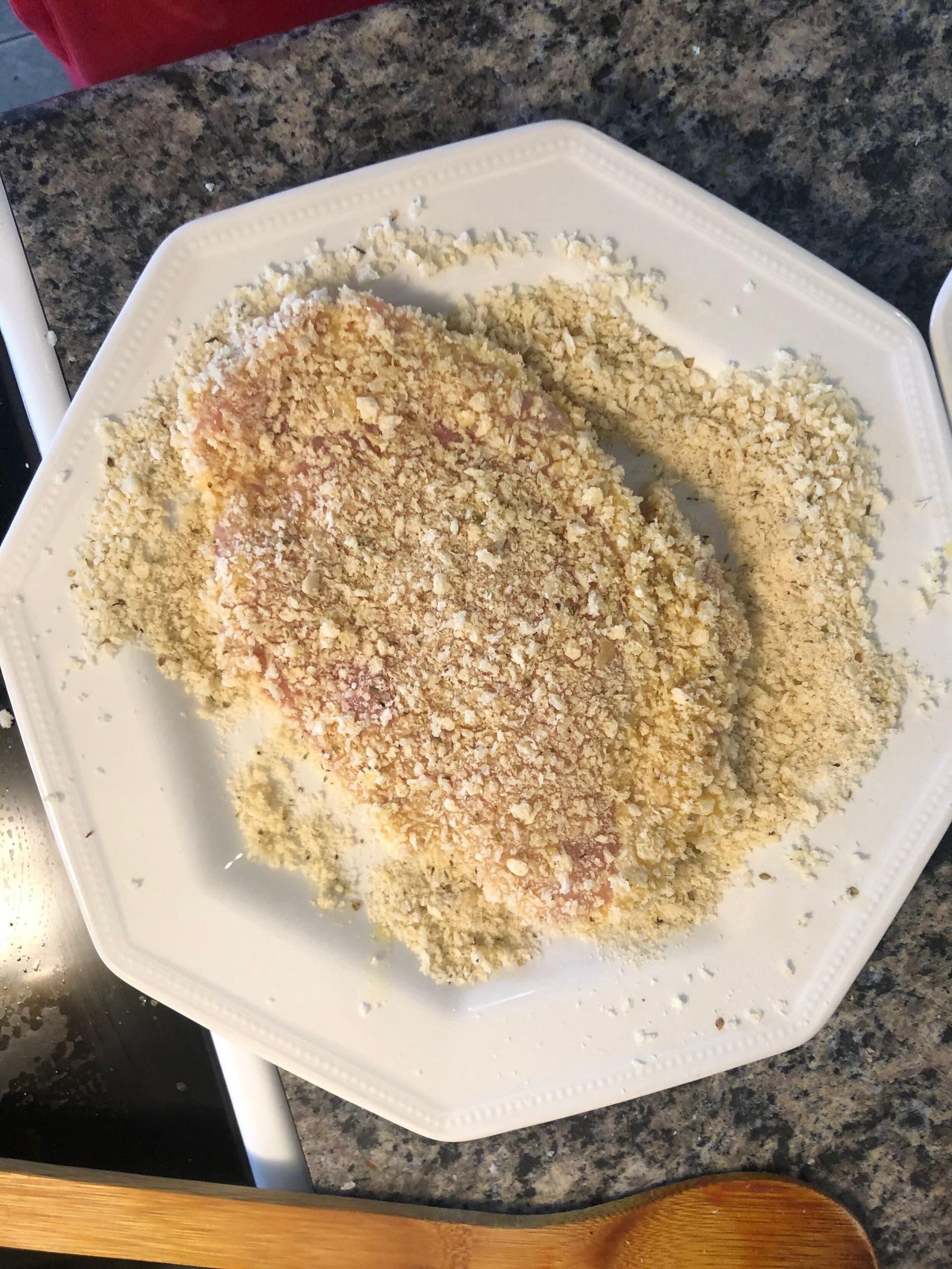 Three breading stations on a white plate: flour, beaten egg, and seasoned breadcrumbs for coating chicken.