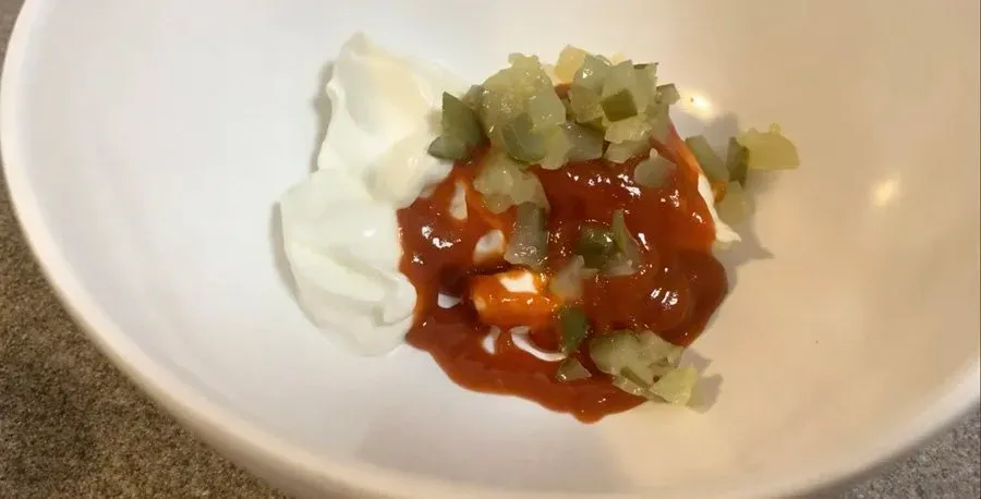 Chipotle mayo sauce with diced green peppers and sour cream in a white bowl.