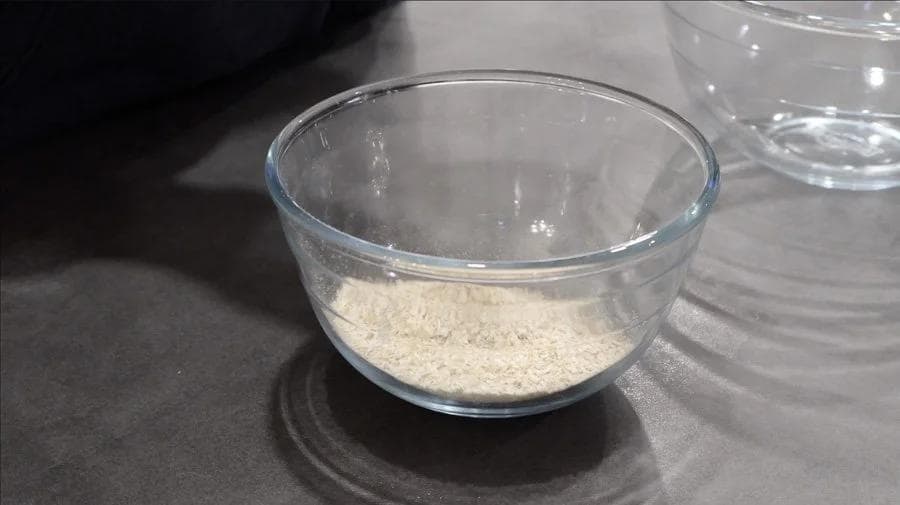 Dry ingredients mixed in a glass bowl: oat flour, pumpkin spice, protein powder, baking powder and salt.
