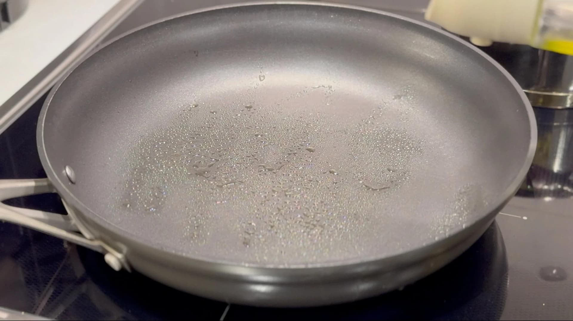 Olive oil heating in a stainless steel pan on a stovetop, glistening and ready for cooking.