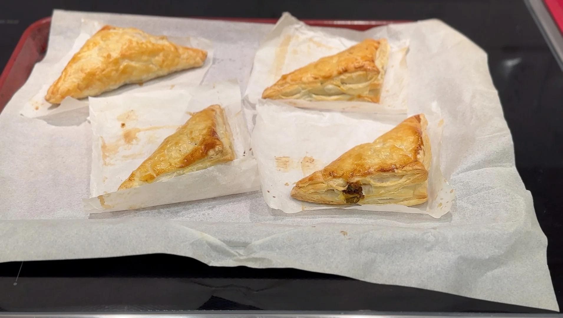 Four golden-brown mushroom puff pastry patties cooling on parchment paper, flaky and crispy.