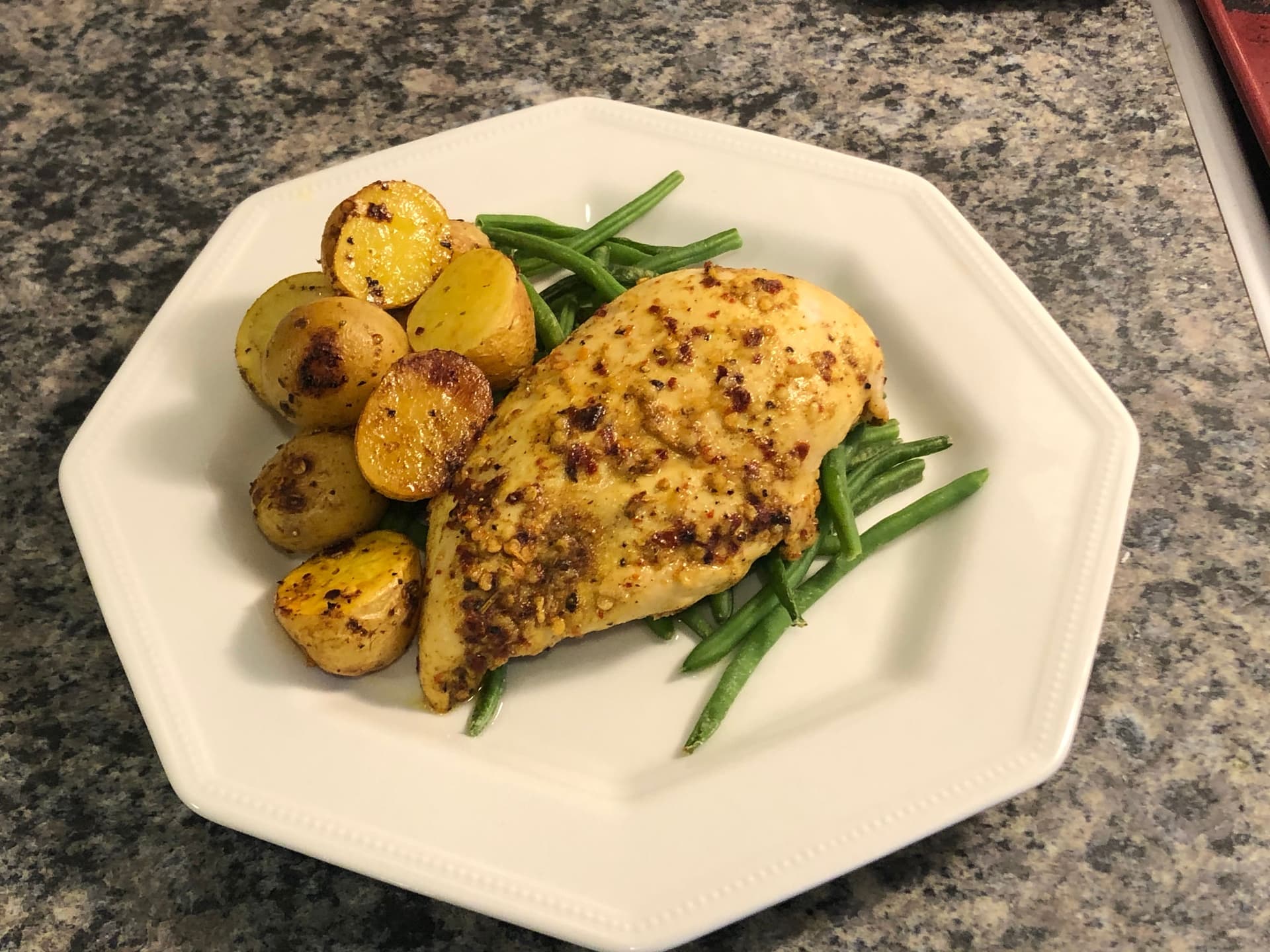 Sheet pan chicken shawarma plated with roasted potatoes and green beans on white dish.