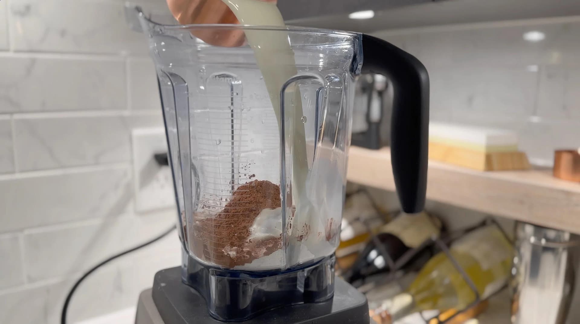 Blender pitcher filled with chocolate crepe batter ingredients during blending process