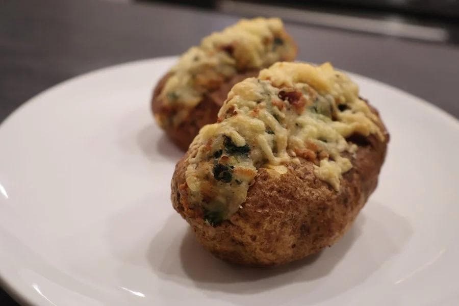 Three golden air-fried twice-baked potatoes with creamy Irish colcannon filling on a white plate.