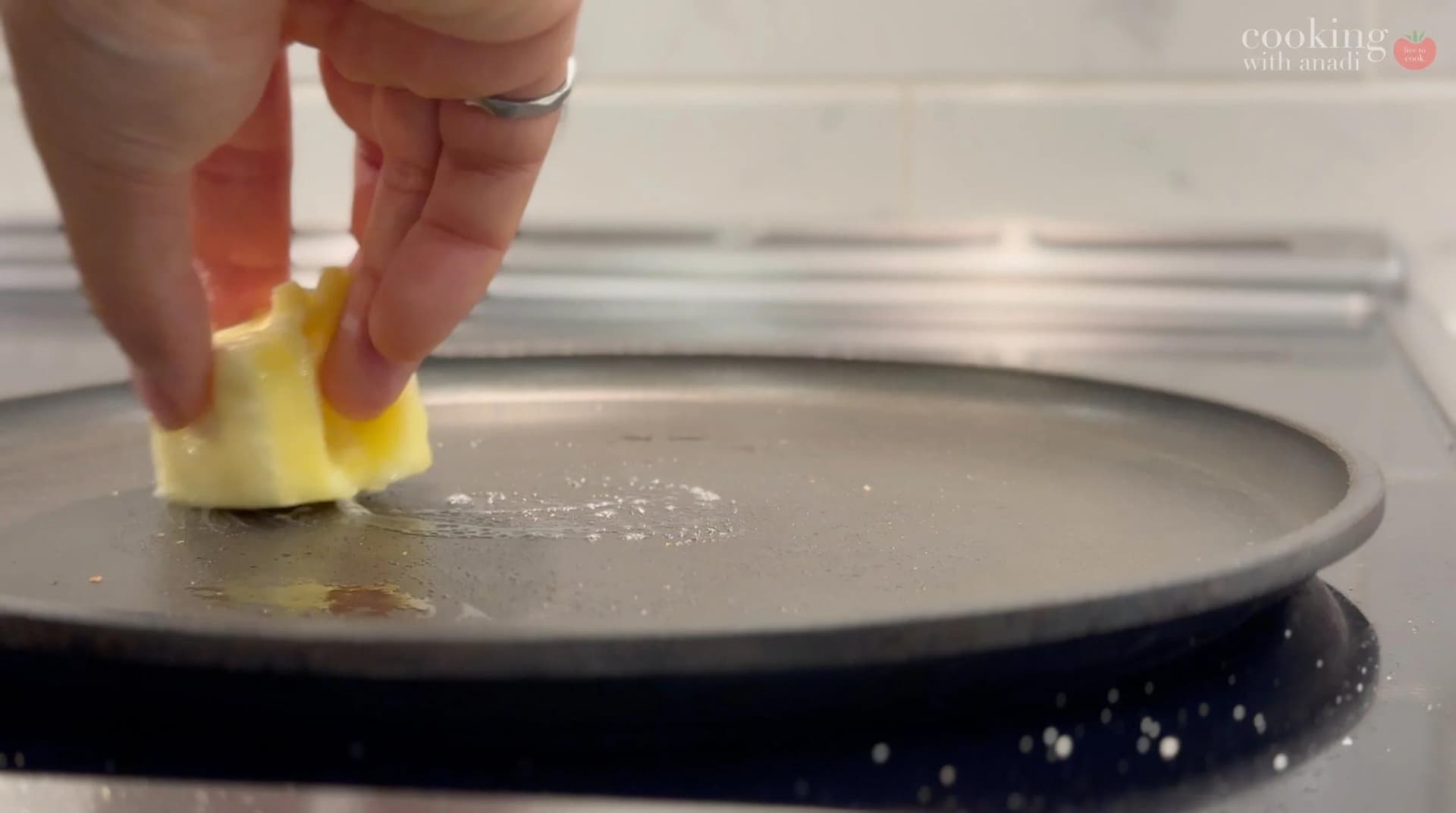 Buttering a hot skillet with a yellow butter square to toast a sandwich.