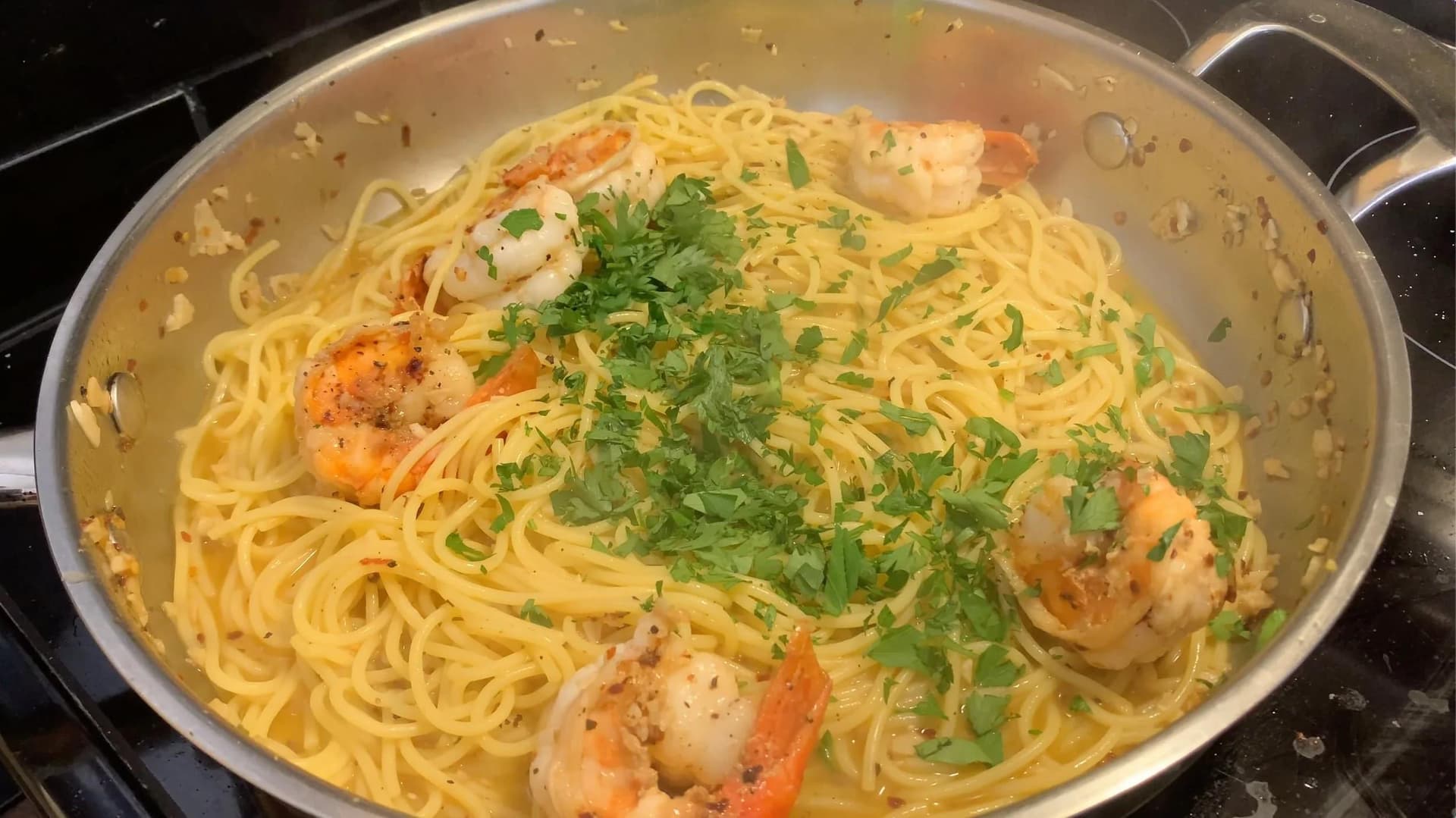 White wine lemon garlic shrimp scampi with spaghetti, topped with fresh parsley and parmesan cheese in a pan.