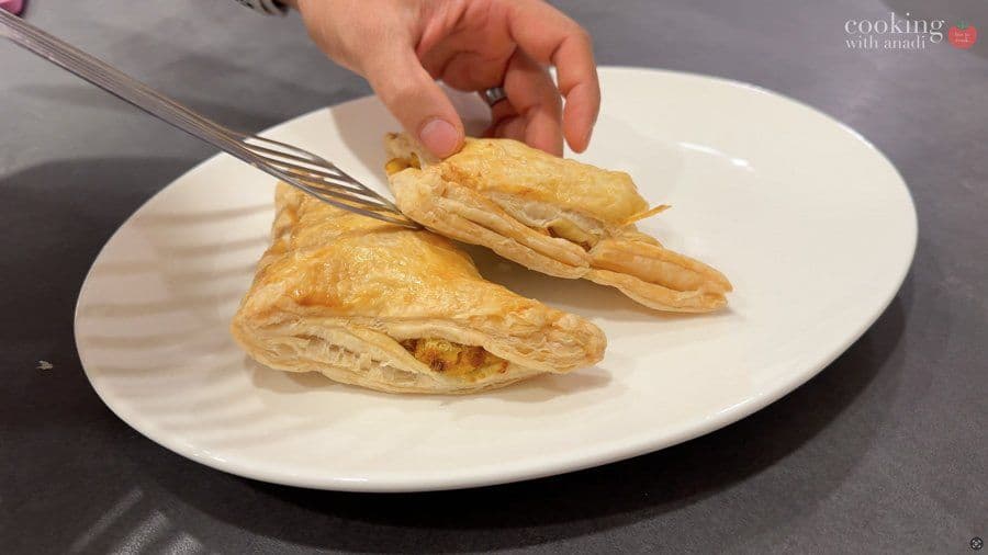 Golden brown air fryer aloo patties being cut open with a fork on a white plate, showing the creamy potato filling inside.