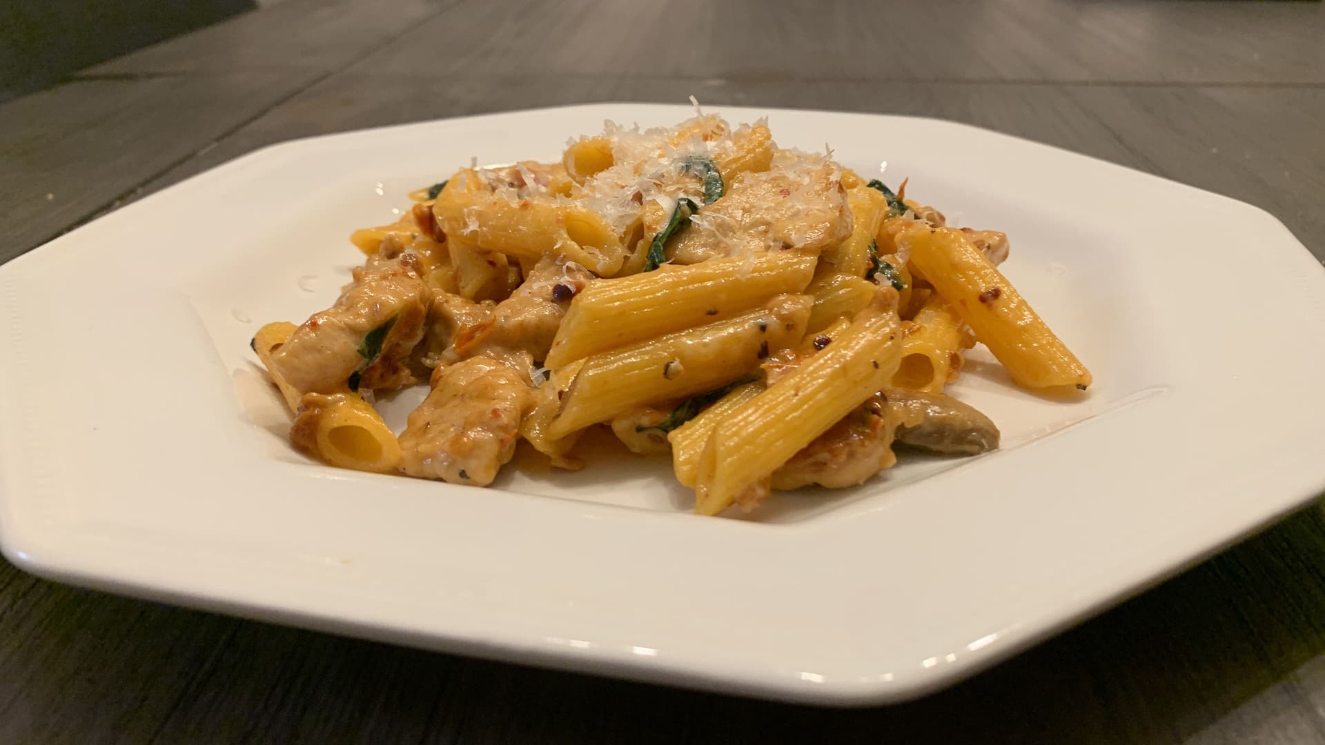 Creamy spicy chicken penne pasta garnished with fresh herbs on a white plate