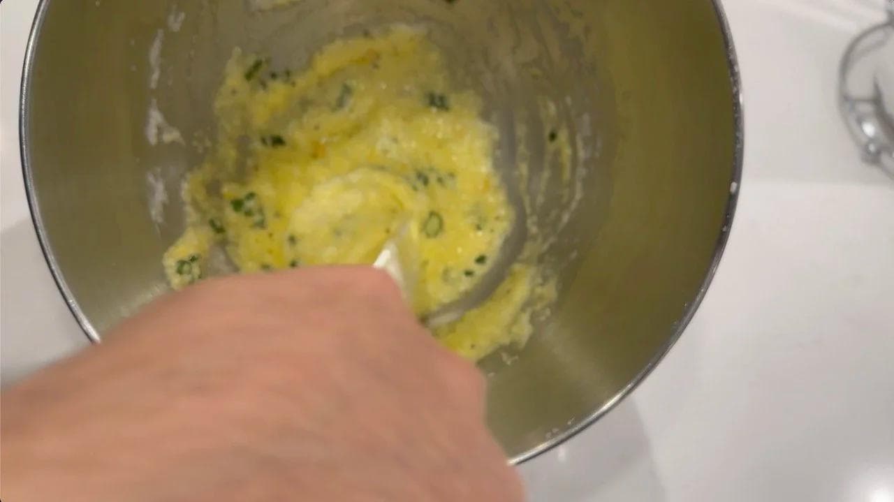 Folding whipped egg whites into yolks in a bowl with a spatula for soufflé mixture.