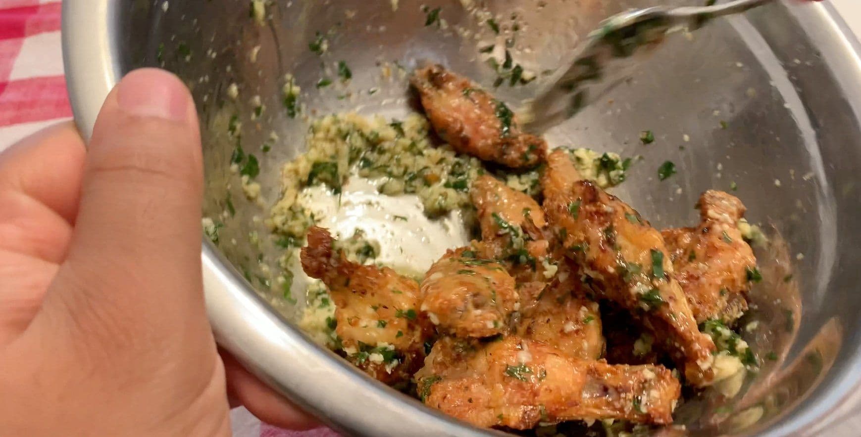 Garlic parmesan chicken wings tossed in creamy herb sauce in a white bowl, garnished with fresh parsley.