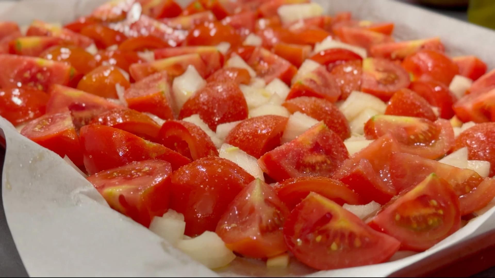 Diced tomatoes and onions on a white plate before roasting for creamy tomato soup.
