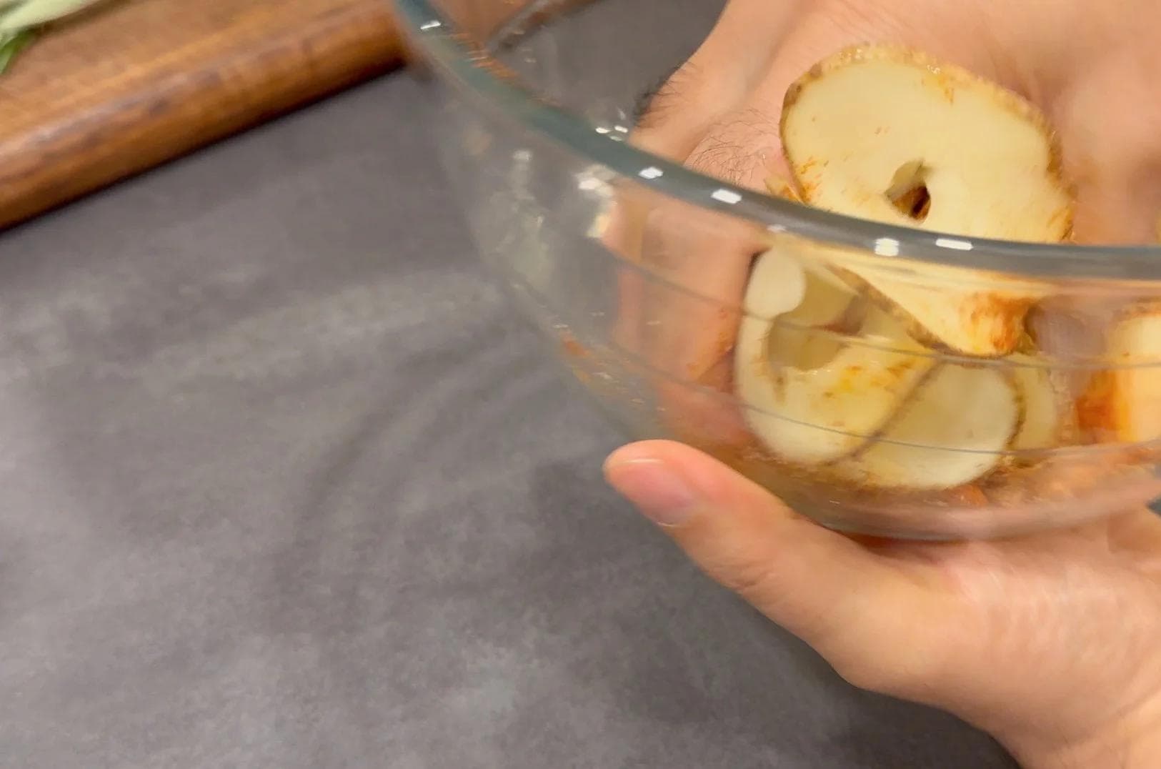Thinly sliced potatoes in a glass bowl being prepared for puff pastry tarts.