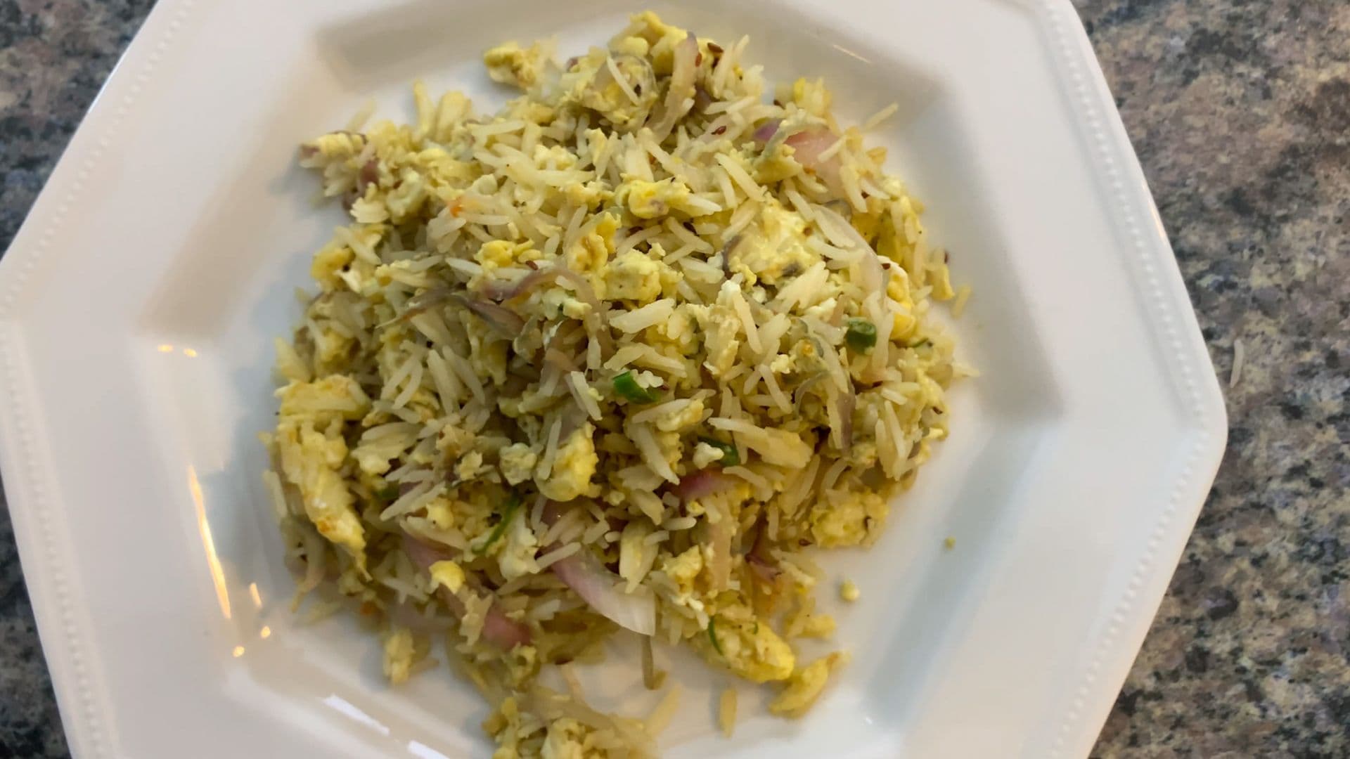 Indian egg fried rice with scrambled eggs, rice, and green peas on a white plate.