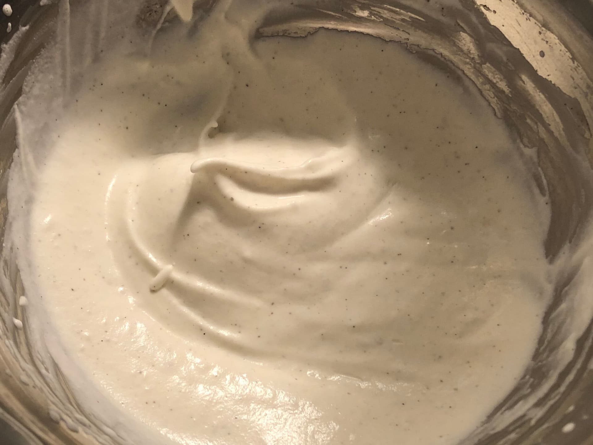 Over-whipped cream in a bowl with stiff peaks pointing upward and a grainy texture