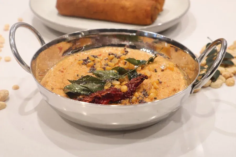 South Indian roasted peanut chutney garnished with curry leaves and red chilies in a serving bowl.