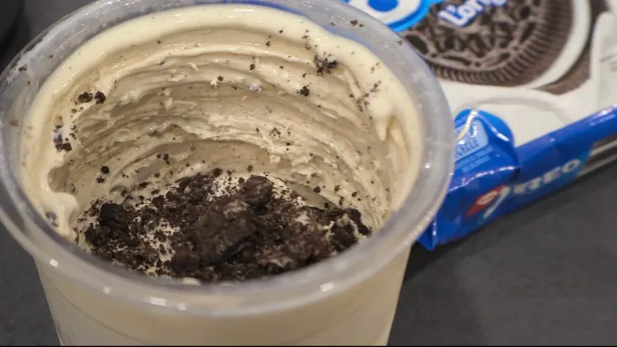 Creamy vanilla soft serve with crushed Oreos being mixed in a container during Ninja Creami preparation