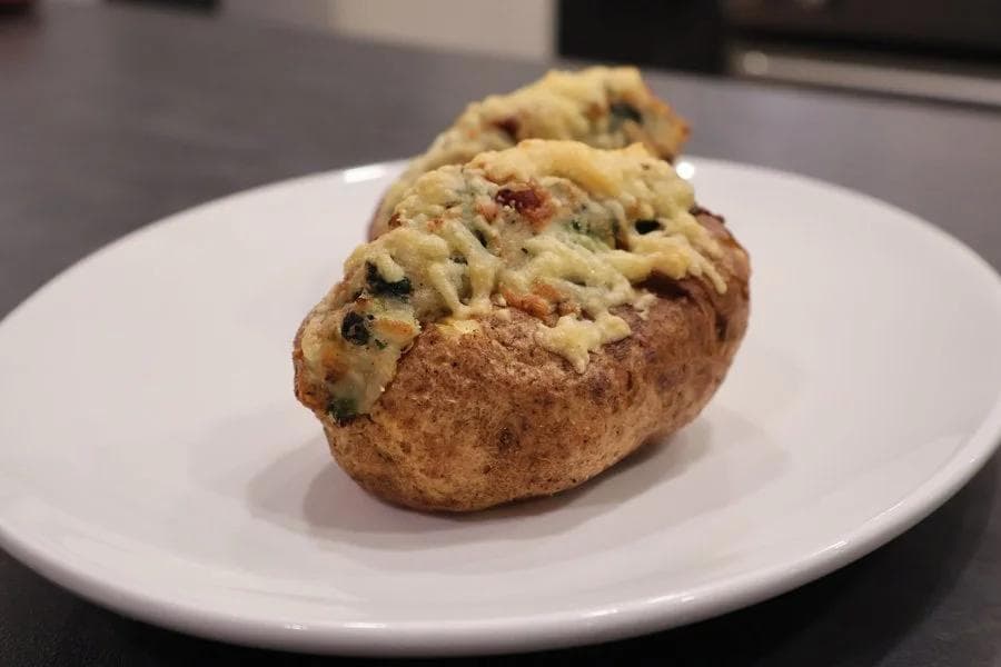 Air fryer twice baked potato topped with creamy Irish colcannon filling on white plate.