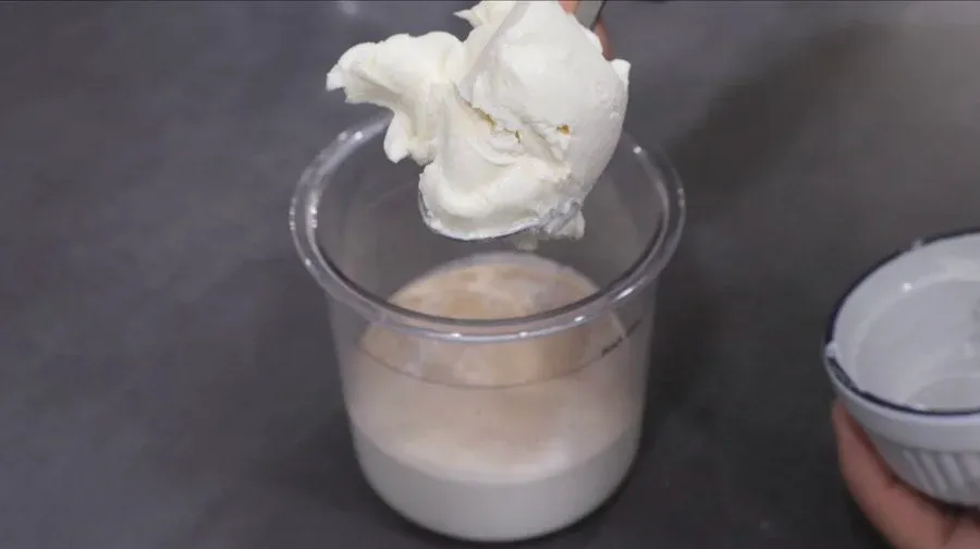 Whipped cream being folded into vanilla ice cream base in a clear container for high protein McFlurry.