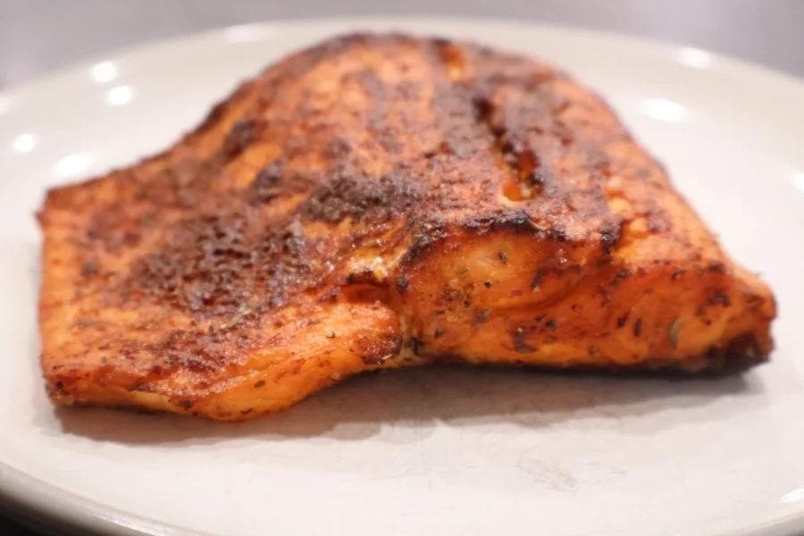 Cooked salmon fillet with cinnamon-sugar seasoning on a white plate.