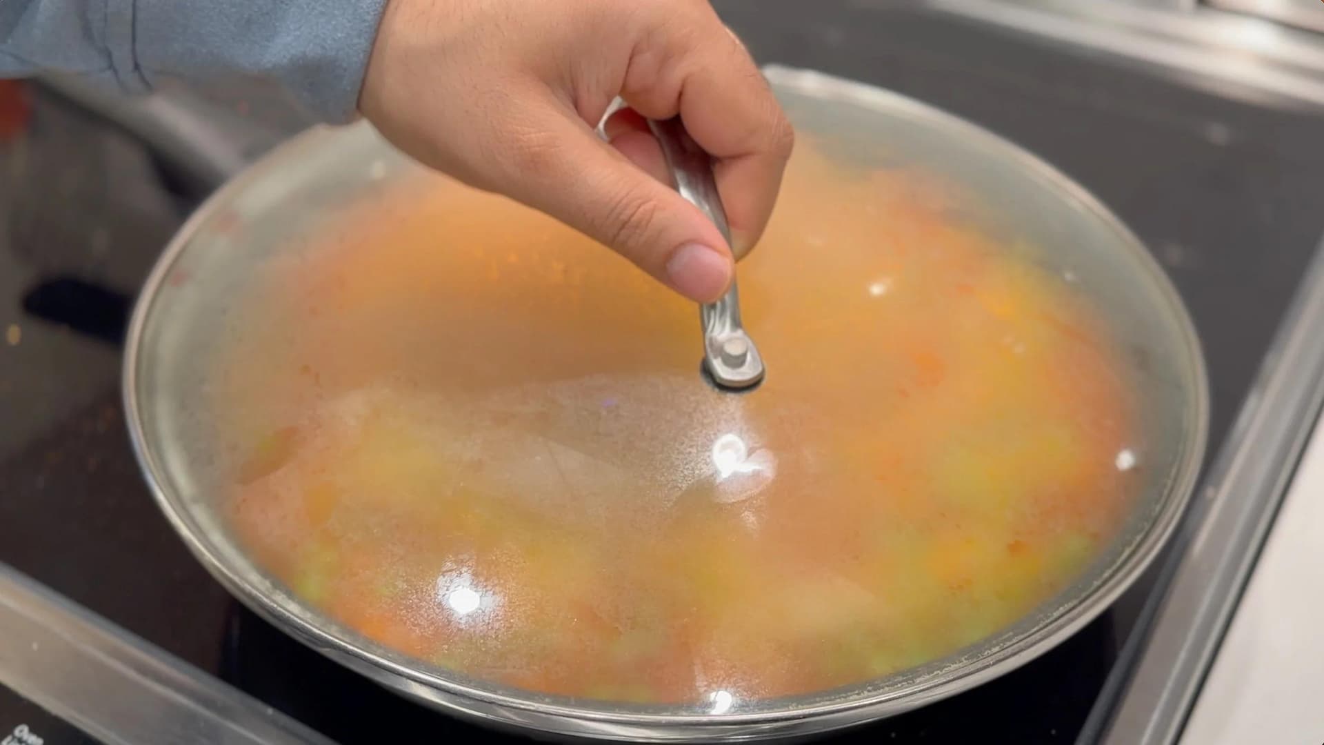 Hand squeezing lemon juice over a pot of cooked Mexican tomato rice with visible carrots and peas.
