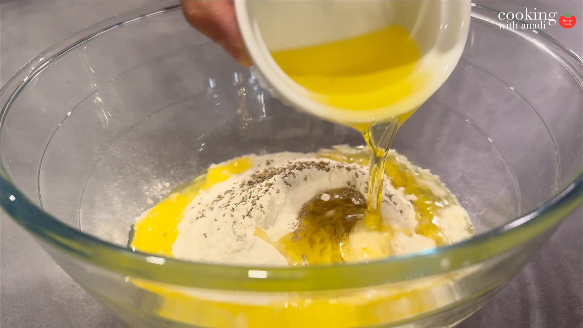 Ghee being poured into a bowl of flour and ajwain to make samosa dough.