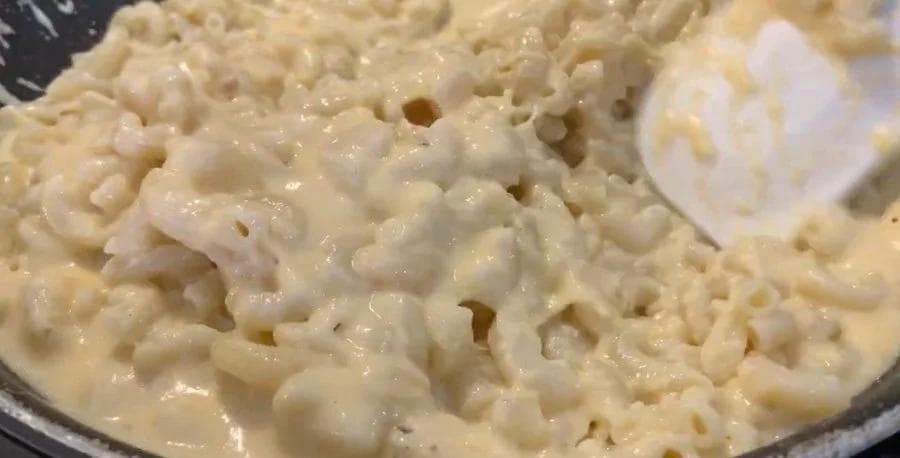 Creamy béchamel sauce coating elbow macaroni with melted cheese in a pot