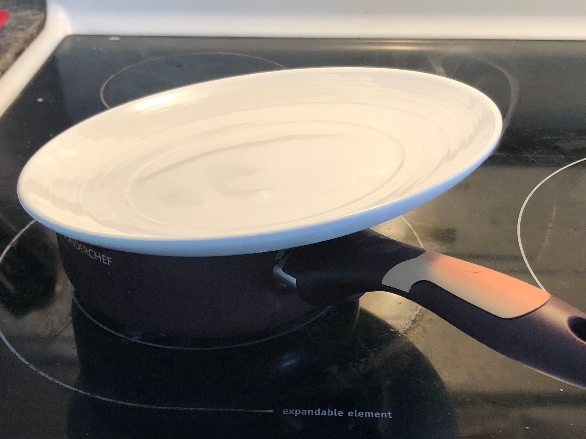 Couscous cooking in a covered blue and white pot on an induction cooktop.