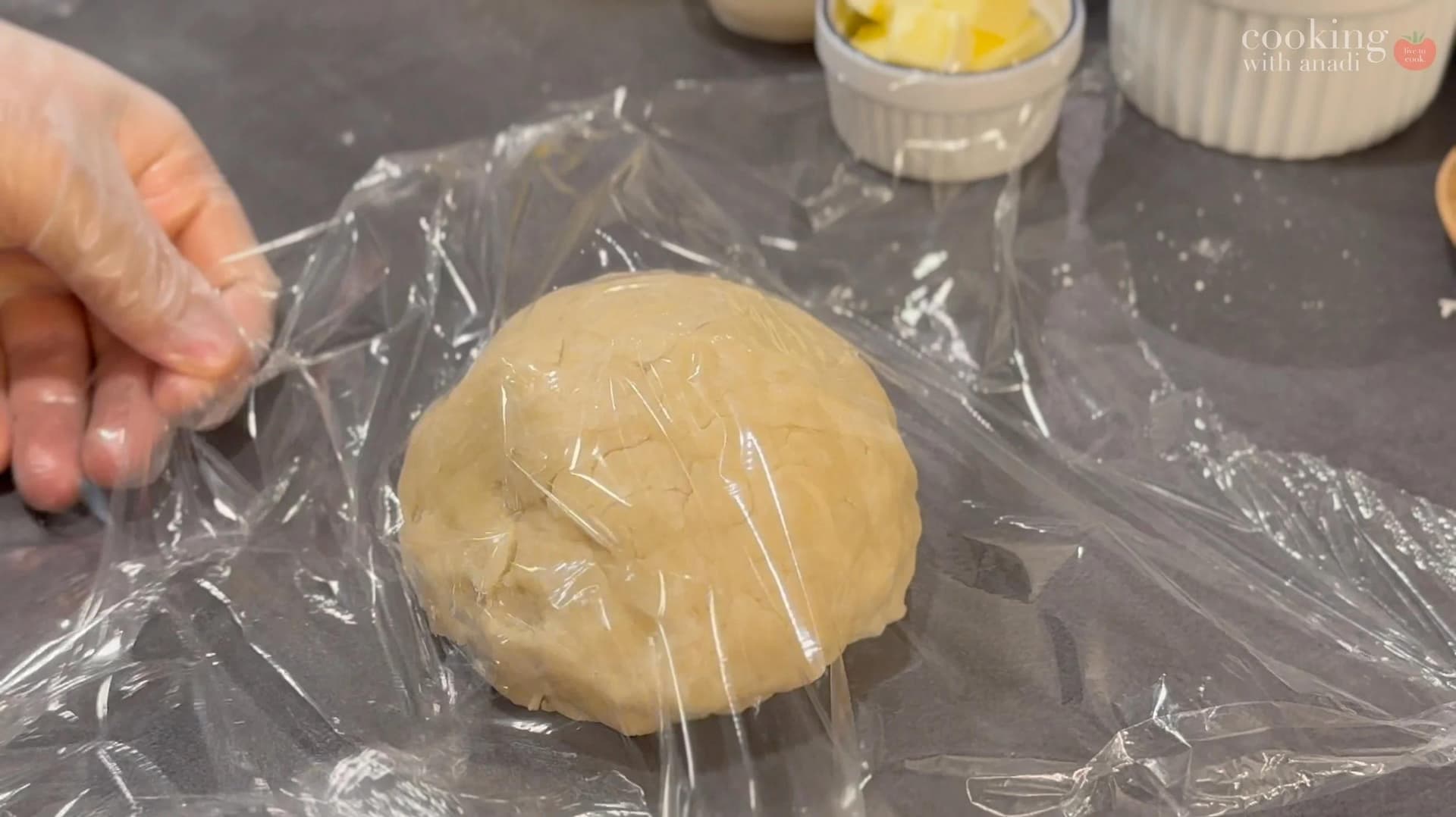 Pie dough shaped into a disk and wrapped in plastic wrap, ready for refrigeration.