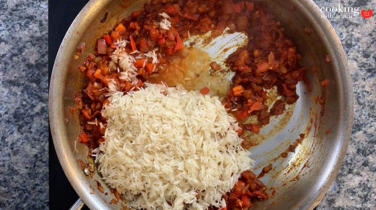 Shredded chicken being added to a pot of cooked tomatoes and rice in a one-pot chicken and rice dish.