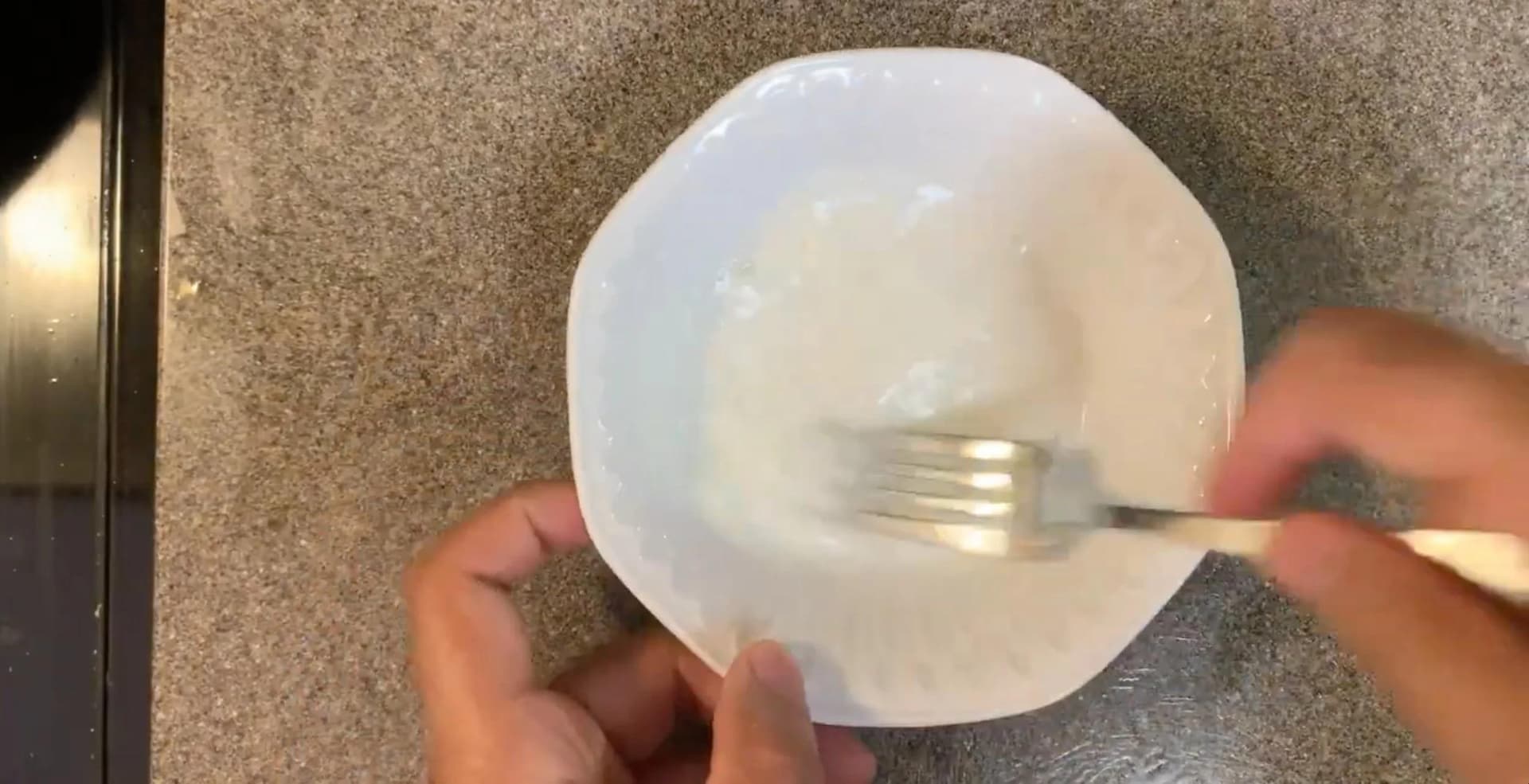 Cornstarch slurry being stirred into gravy with a fork on a white plate.