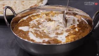 Creamy dal makhani simmering in a steel bowl with butter and cream swirled on top.