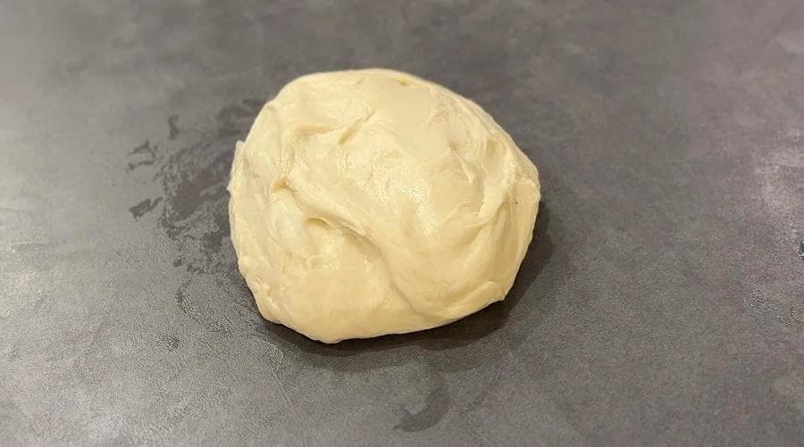 Ball of stretchy dough on gray surface, ready to be shaped into oval for Canadian Beavertails.