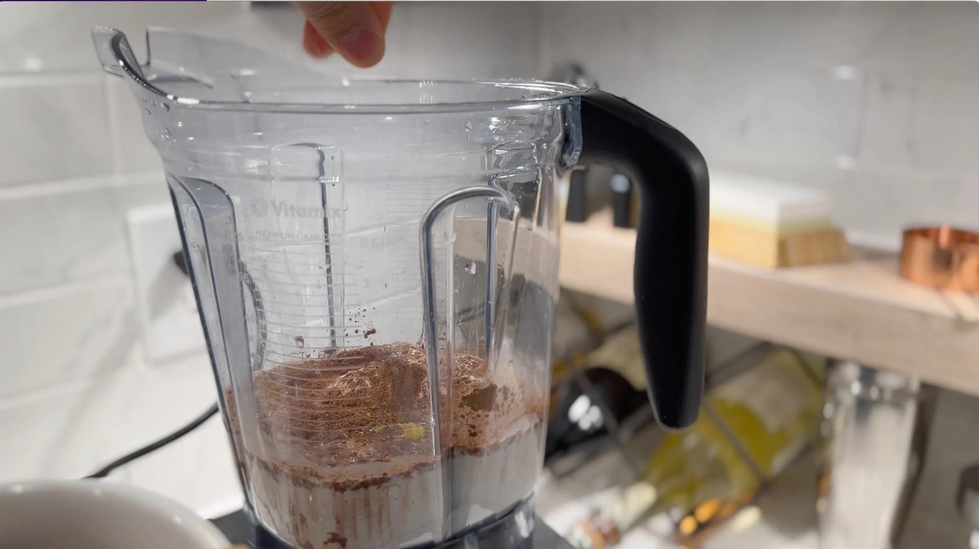 Chocolate crepe batter blended in a food processor pitcher, showing combined dry and wet ingredients.