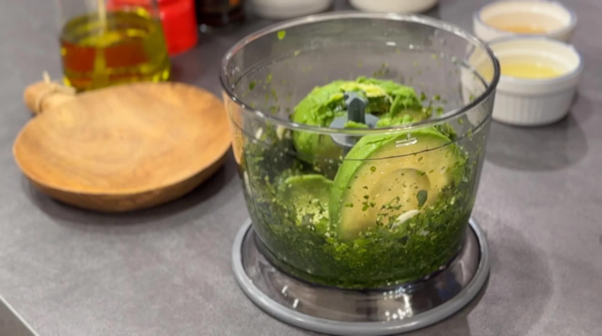 Green goddess dressing being blended in a food processor with avocado, herbs, and creamy ingredients visible.