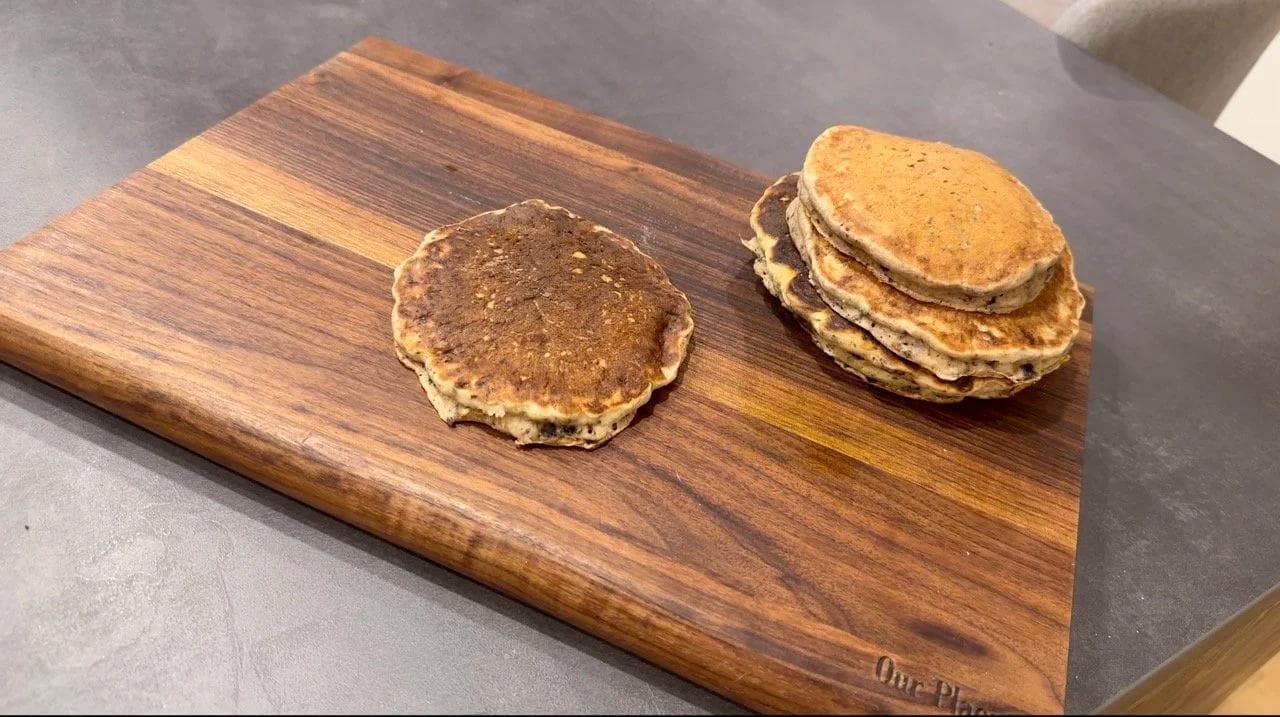 Two stacks of gluten-free pancakes layered with cream cheese glaze and crushed Oreos on a wooden board.