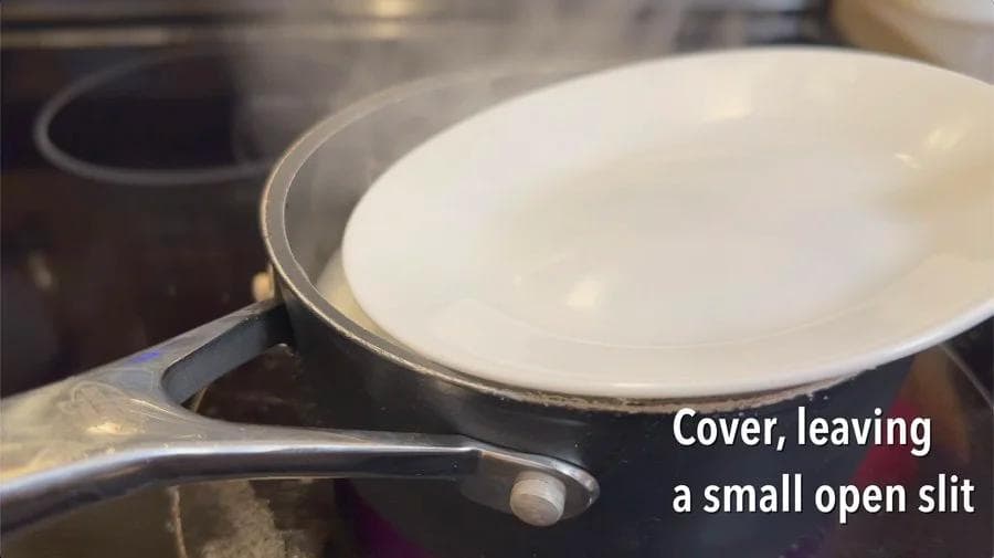 Pot of rice with white lid partially covering it, leaving a small slit open for steam to escape.