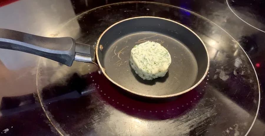 Melted garlic butter being poured over a mound of breadcrumb mixture in a skillet.