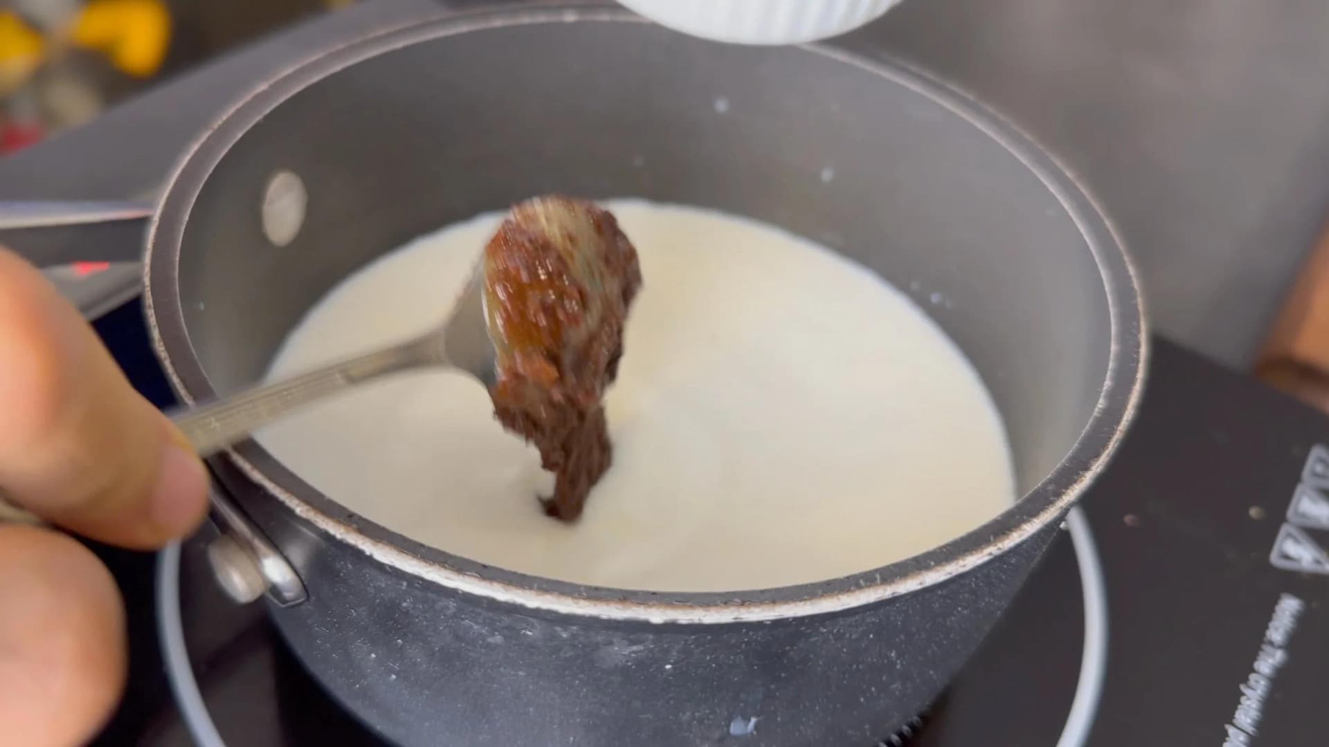 White chocolate being added to steaming milk in a saucepan for sugar cookie latte syrup.