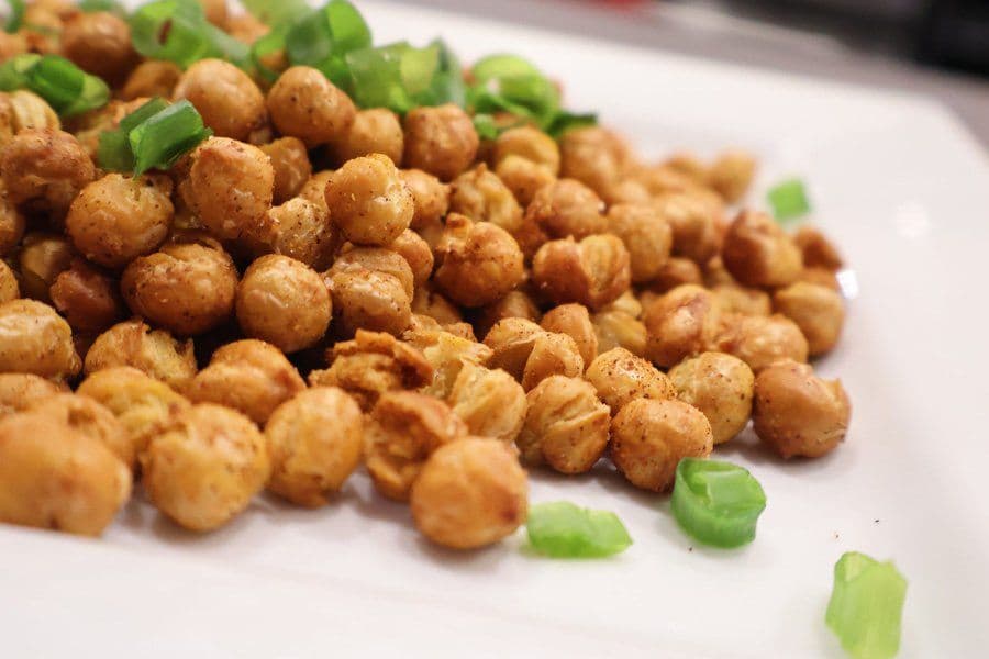 Crispy air fryer chickpeas garnished with green onions on a white plate